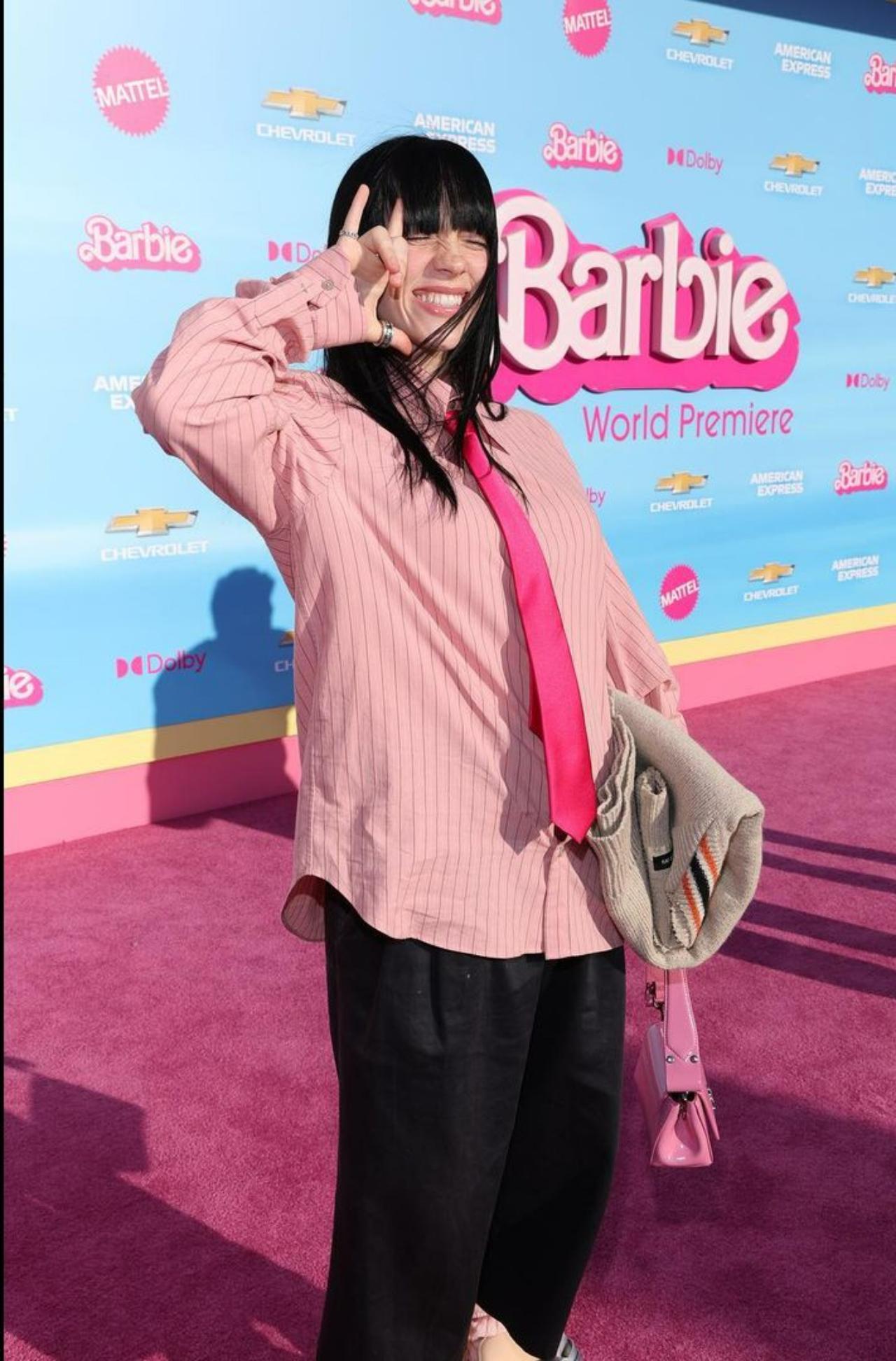 It`s not Billie Eilish if she doesn`t make headlines at every event she attends. The LA premiere ditched the traditional red carpet for a fashionable `pink` carpet stamped with the iconic Barbie logo. Billie Eilish sported giant shoes, short pants and a red tie. Mattel, are you taking notes?